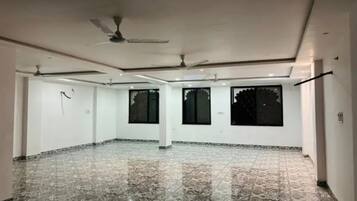 Amplia habitación con piso de mármol, ventiladores de techo y ventanas grandes.