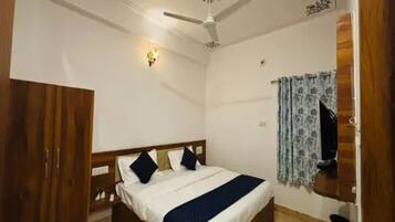 Un dormitorio con cama, ventilador de techo, luz empotrada en la pared y ventana con cortinas.