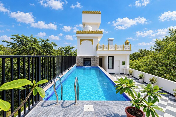 A swimming pool with a checkered floor, surrounded by a black fence and potted plants.
