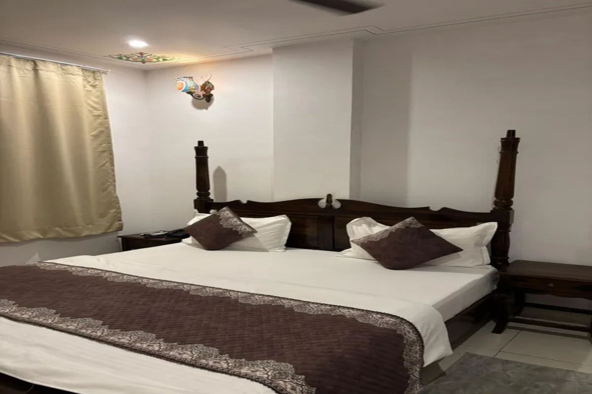 A neatly made bed with a brown blanket, a wooden headboard, and two bedside tables with lamps.
