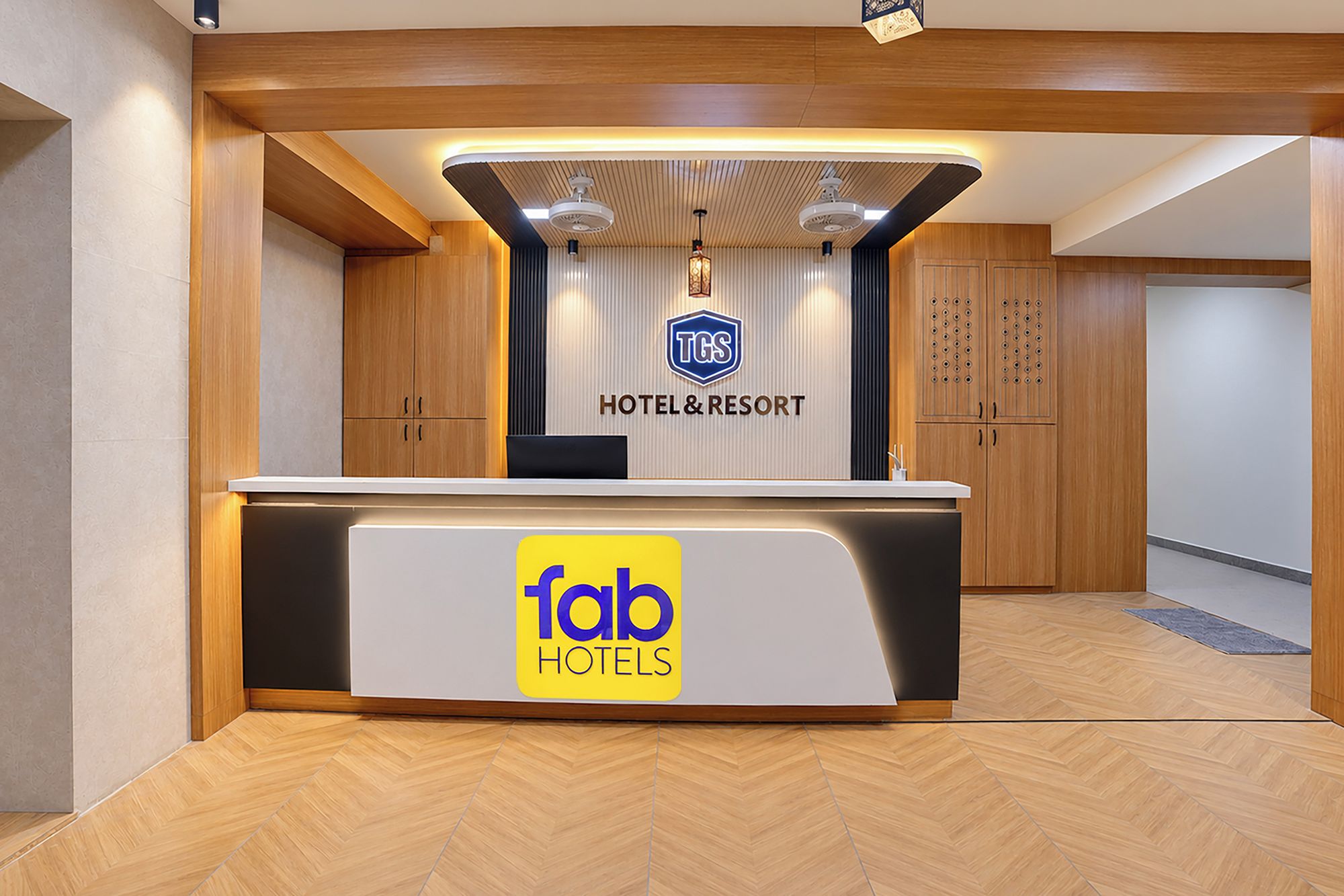 Un comptoir d’accueil d’hôtel avec le logo de « fab hotels » et une enseigne indiquant « TGS HOTEL & RESORT ».