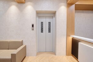 An elevator with a digital display, a reception desk, and a seating area.