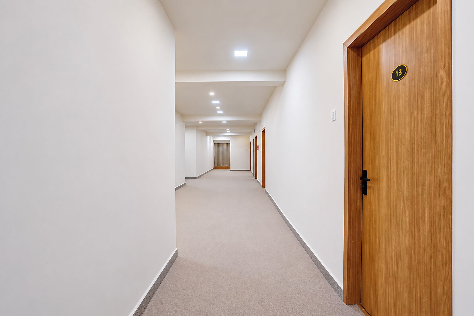 Corredor com porta de madeira marcada com o número 13, dando acesso a um quarto.