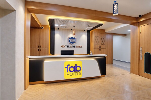 A hotel reception desk with a modern design, a logo for TGS Hotel & Resort, and a sign for Tab Hotels.