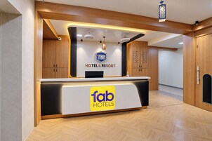 Un mostrador de recepción de hotel con diseño moderno, un logotipo para TGS Hotel & Resort y un cartel de Tab Hotels.