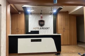 Bancada de recepção com uma placa indicando 'HOTEL & RESORT' e um logotipo acima.