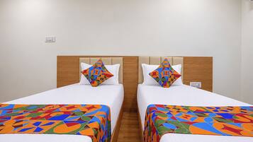 Habitación de hotel con dos camas, cada una con un edredón y almohadas a juego de estampado geométrico colorido.