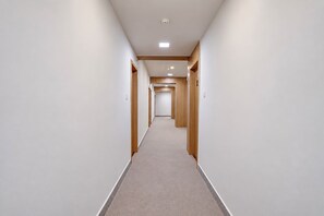 Un pasillo con piso alfombrado, paneles de madera en las paredes e iluminación empotrada.
