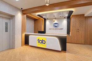A hotel reception desk with a logo for 'fab hotels' and a sign for 'TGS HOTEL & RESORT'.