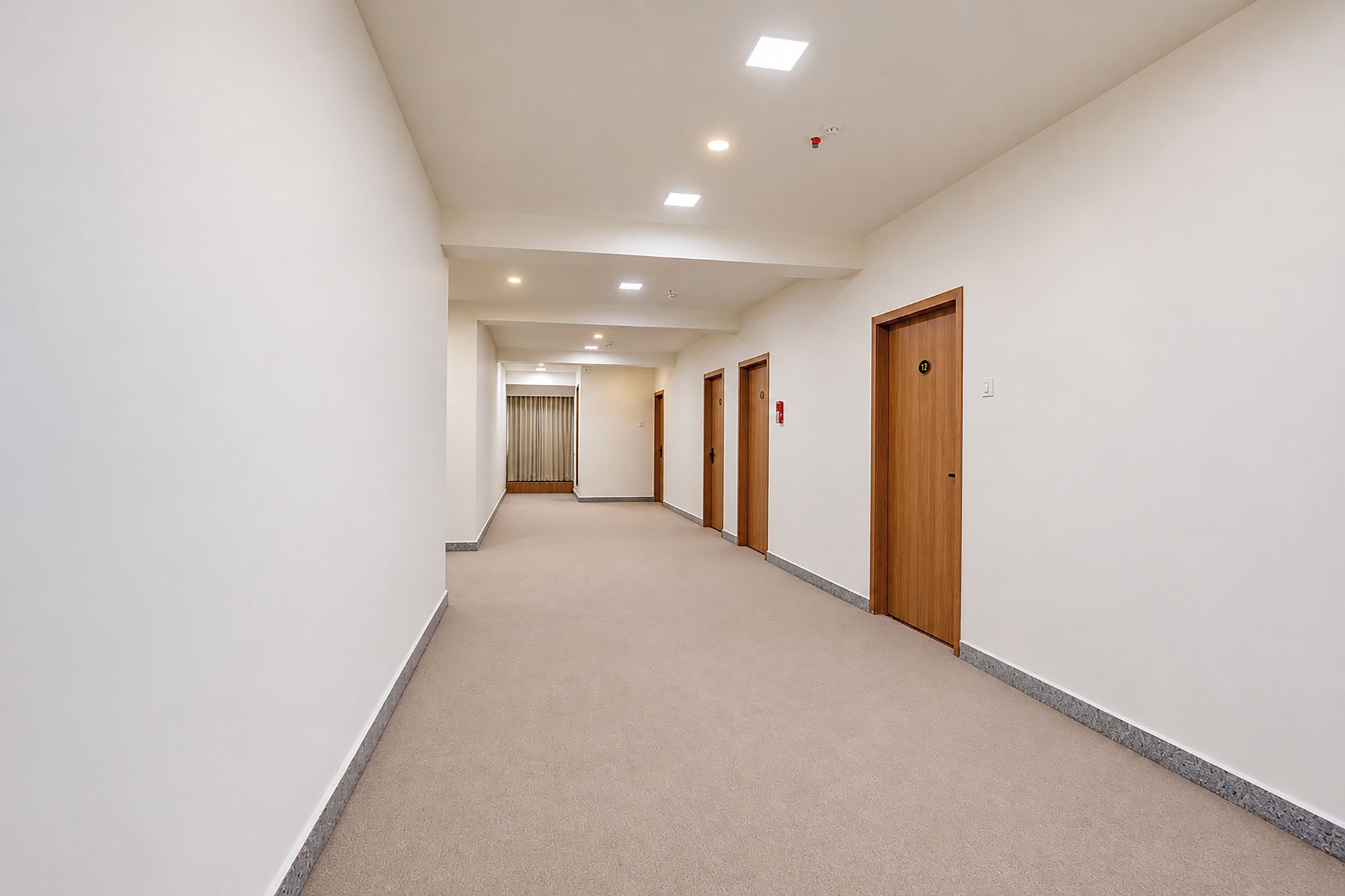 Un pasillo con puertas a un lado y una cortina al final.