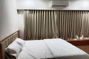Quarto de hotel com cama, cortinas e ar condicionado.