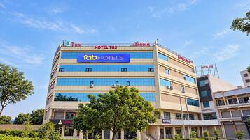 A multi-story hotel with 'HOTEL TGS' signage, 'fabHOTELS' branding, and various commercial establishments on the ground floor.