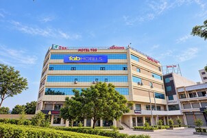 Un hotel de varios pisos con letreros que indican 'HOTEL TGS', la marca 'fabHOTELS' y diversos comercios en la planta baja.