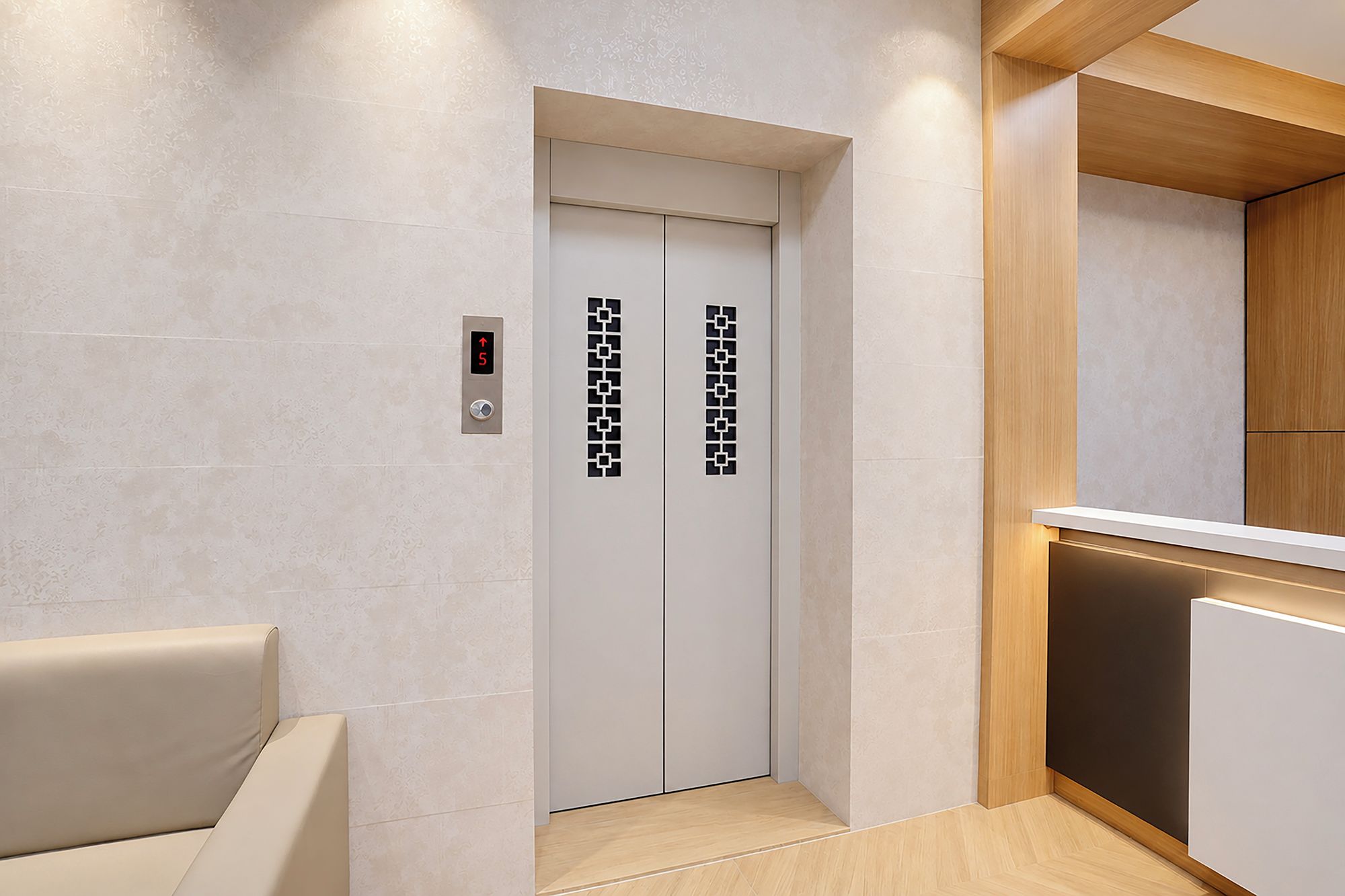 Un moderno ascensor con pantalla digital, mostrador de madera y pared color beige.