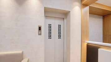 Un moderno ascensor con pantalla digital, mostrador de madera y pared color beige.