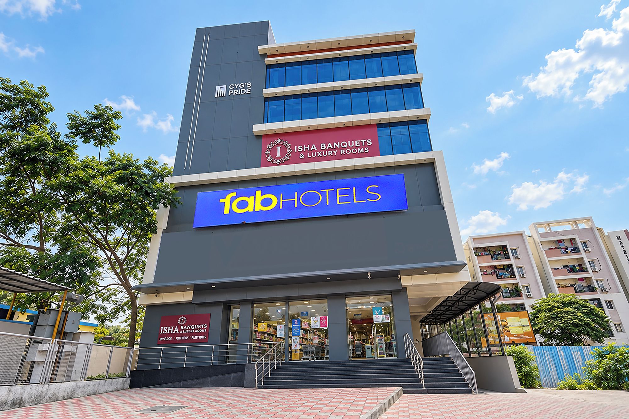 Un hôtel reconnaissable à son grand panneau « fabHOTELS », à ses nombreux étages et à son entrée bien visible, accessible par quelques marches.