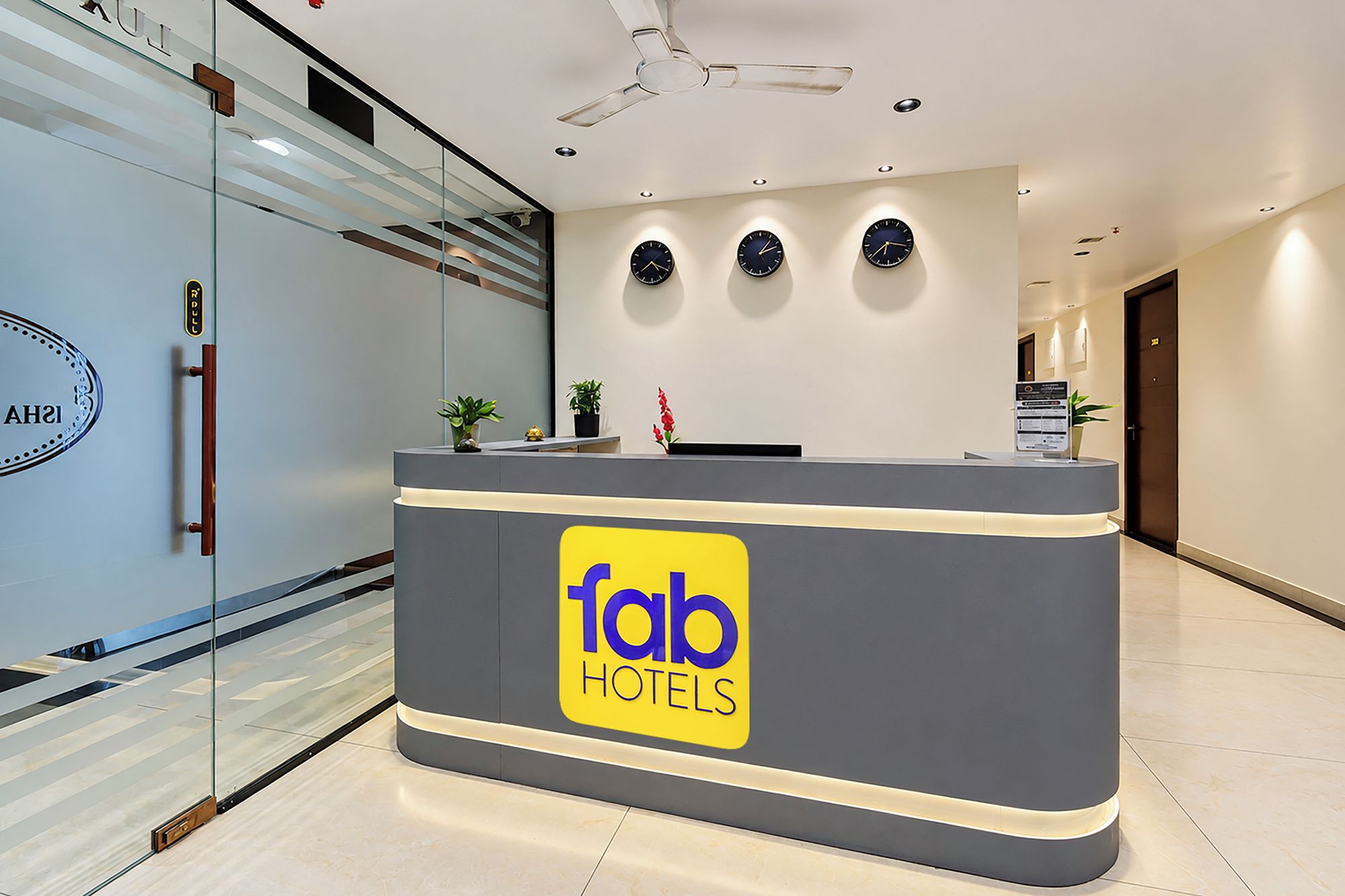 A reception desk with a logo for 'fab hotels' and three clocks on the wall.