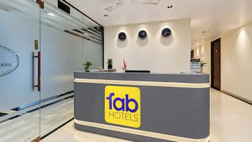 Una recepción con el logotipo de 'fab hotels' y tres relojes en la pared.