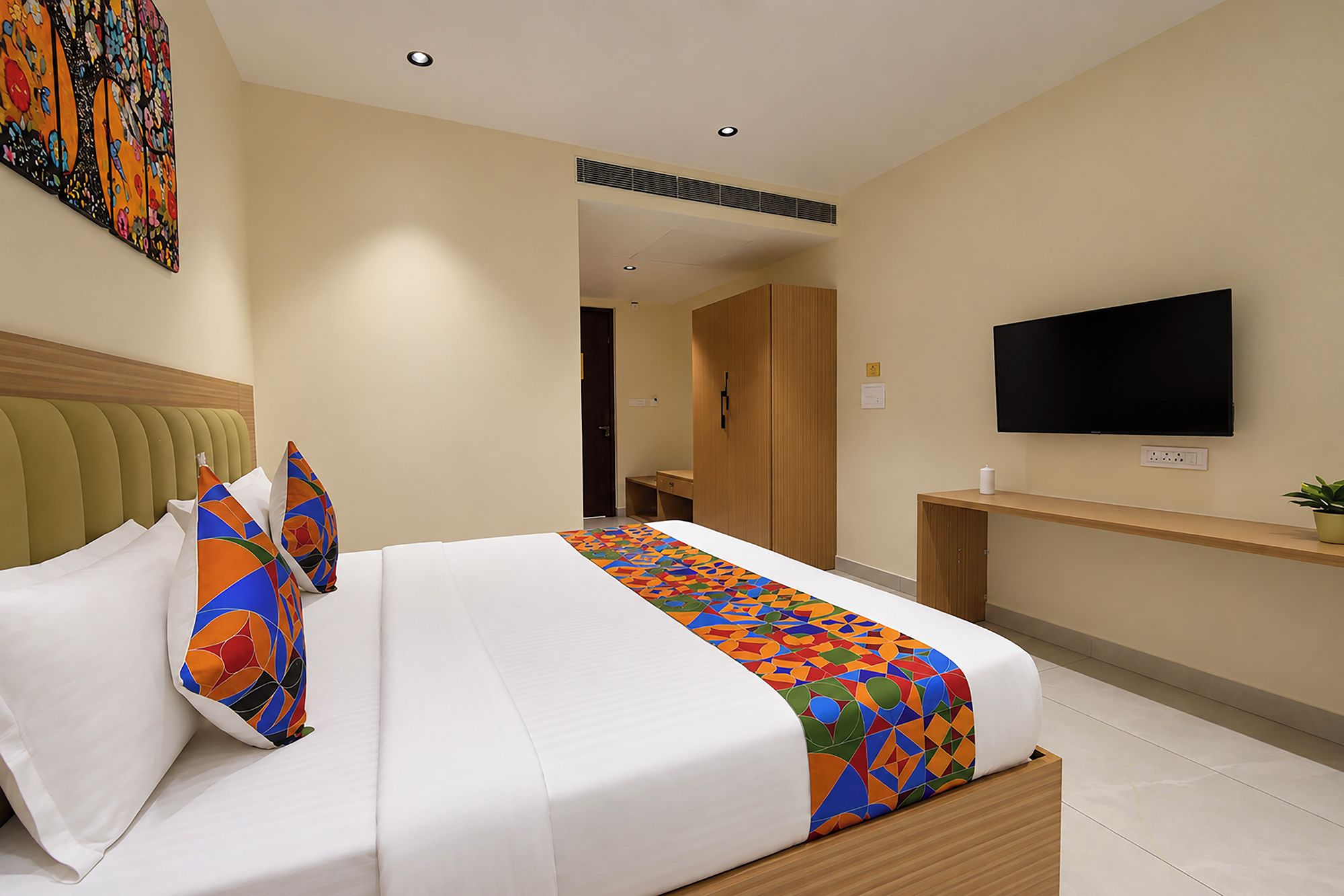 Une chambre d’hôtel équipée d’un lit, d’une télévision, d’un bureau et d’une porte donnant sur une autre pièce.