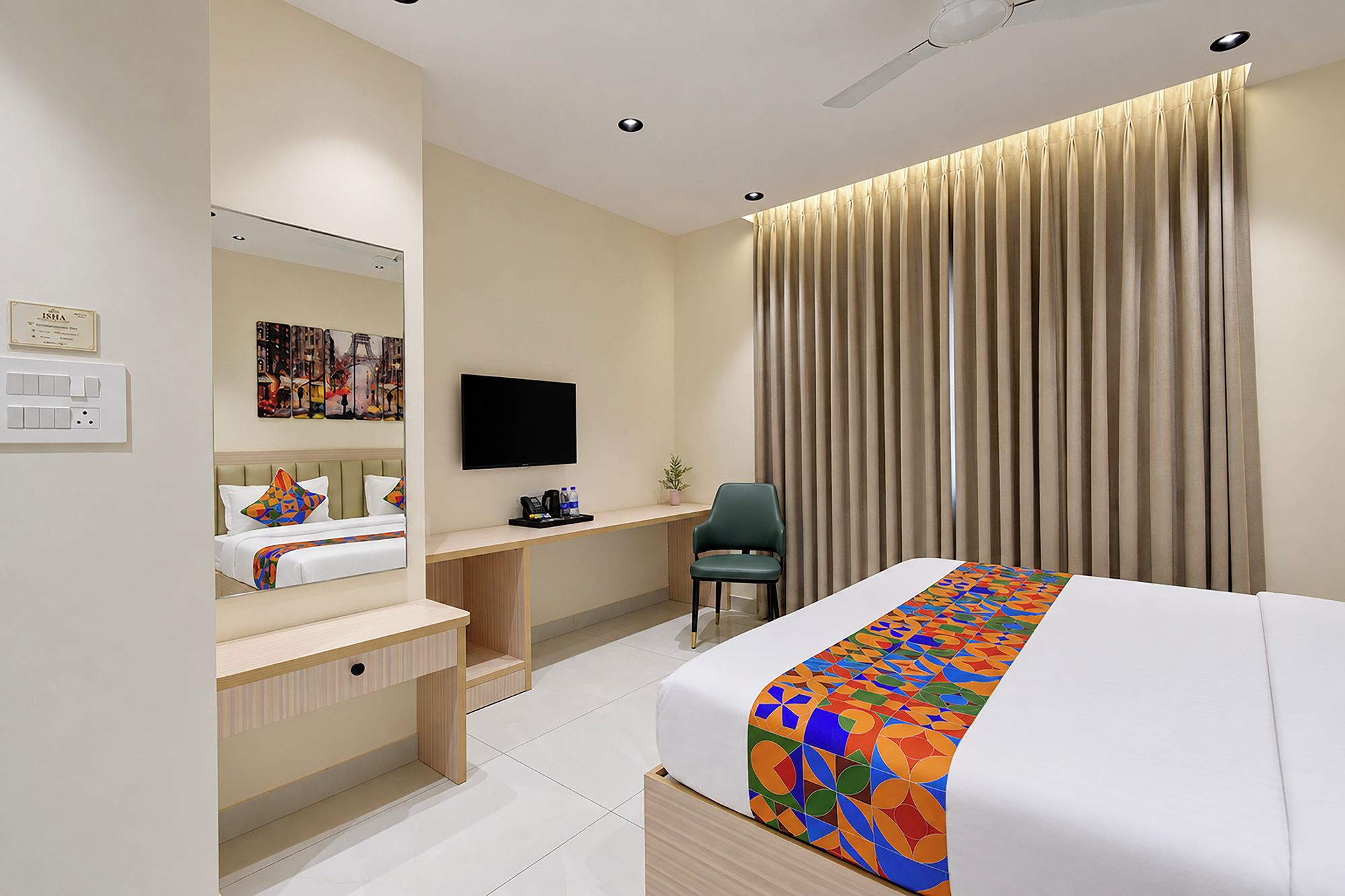 Une chambre d’hôtel avec un lit, un bureau, une chaise, une télévision et une grande fenêtre avec des rideaux.