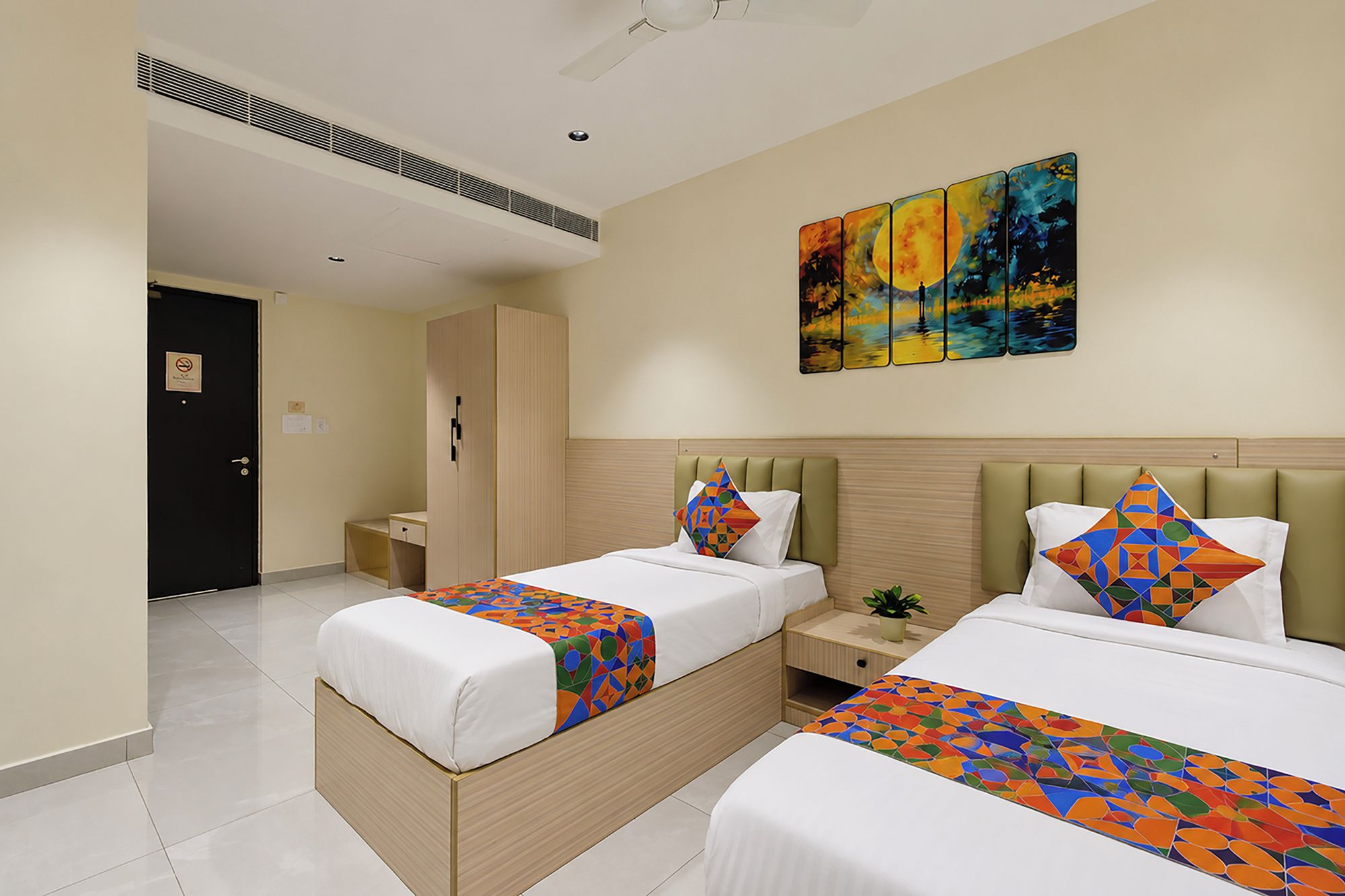 A hotel room with two beds, a nightstand, a wardrobe, and a painting on the wall.