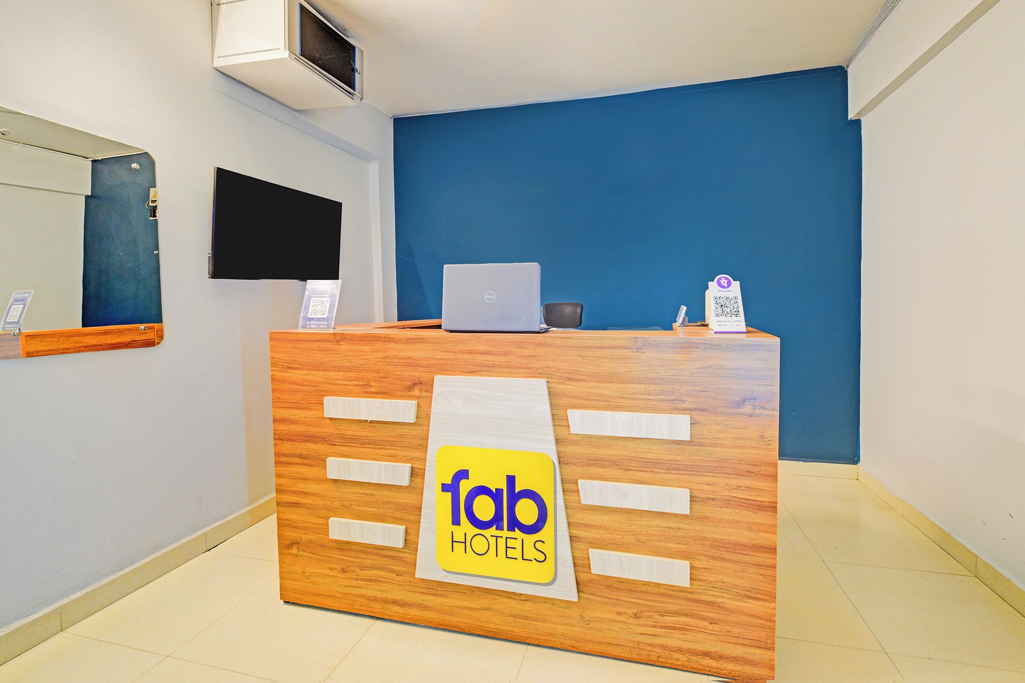 Una mesa de recepción con una computadora portátil, un código QR y un letrero que dice 'fab hotels'.