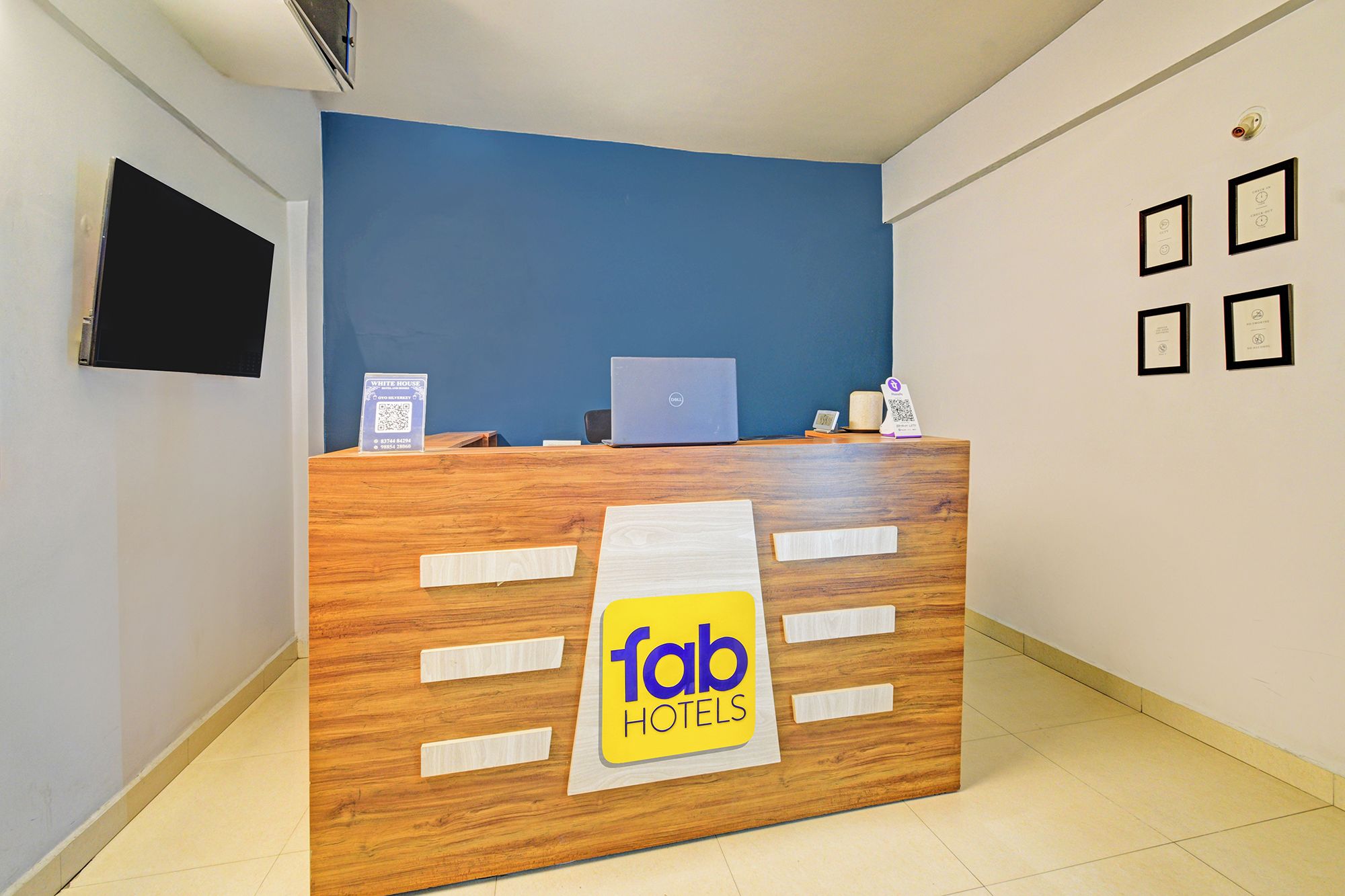 A reception desk with a sign for Fab Hotels, a laptop, a phone, and a QR code.