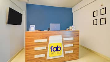 A reception desk with a sign for Fab Hotels, a laptop, a phone, and a QR code.