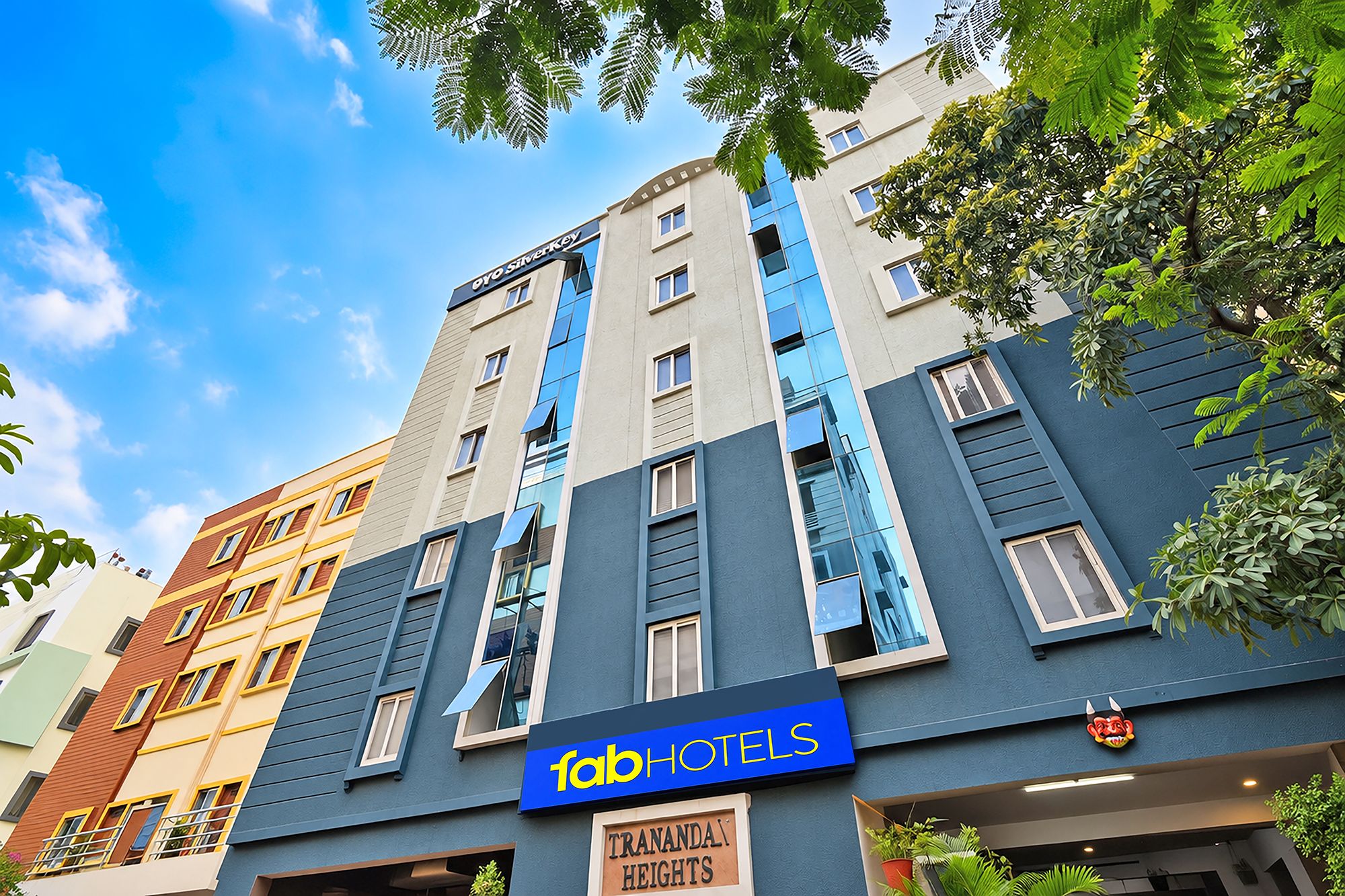Un hotel de varios pisos con un letrero llamativo que dice 'fob hotels', balcones y un letrero que indica 'Tranantha Heights'.