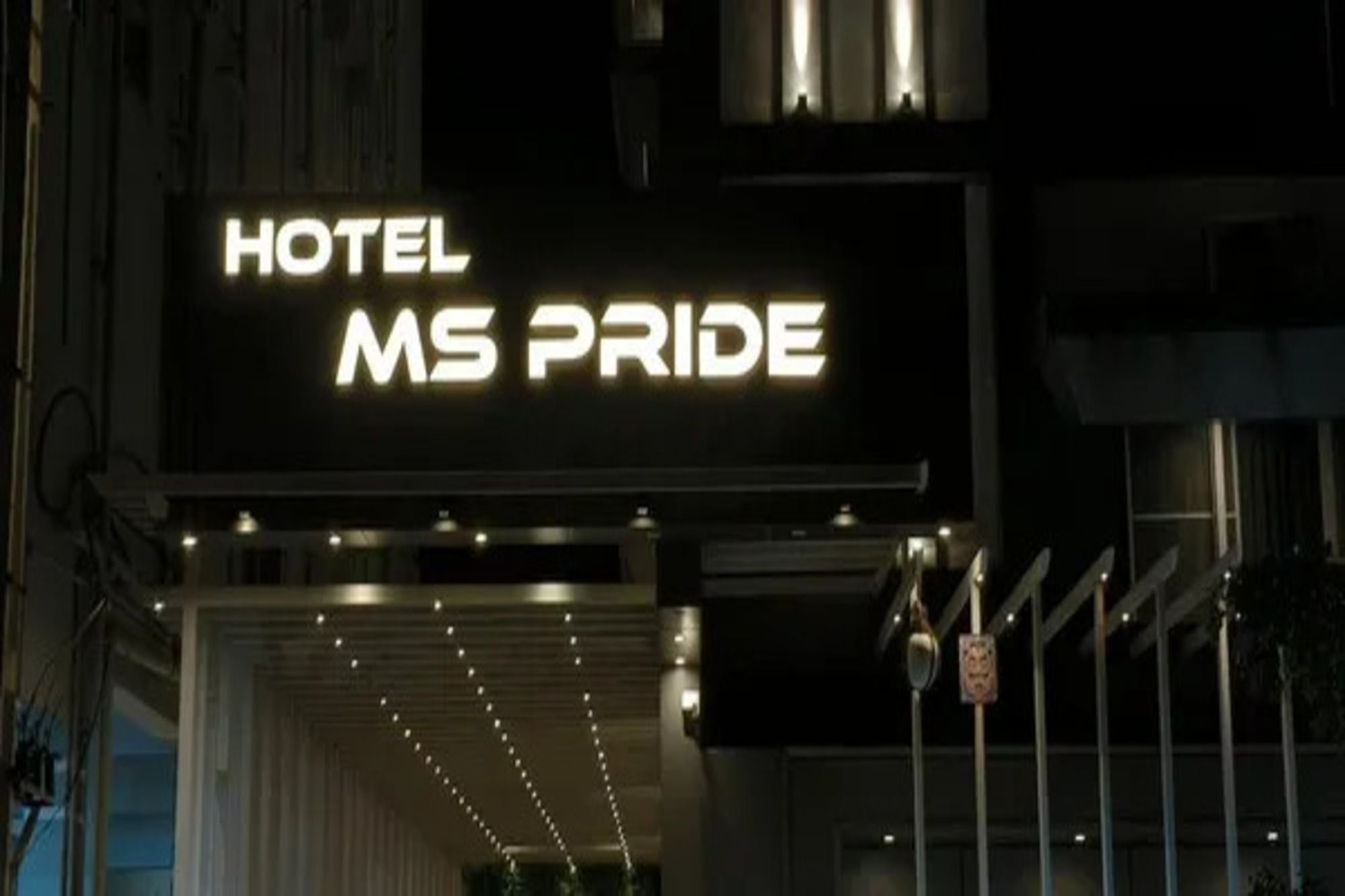 Segnaletica luminosa di un hotel con il nome 'MS PRIDE' illuminato in bianco.