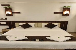 Habitación de hotel con una cama grande, dos mesitas de noche y luces fijadas a la pared.