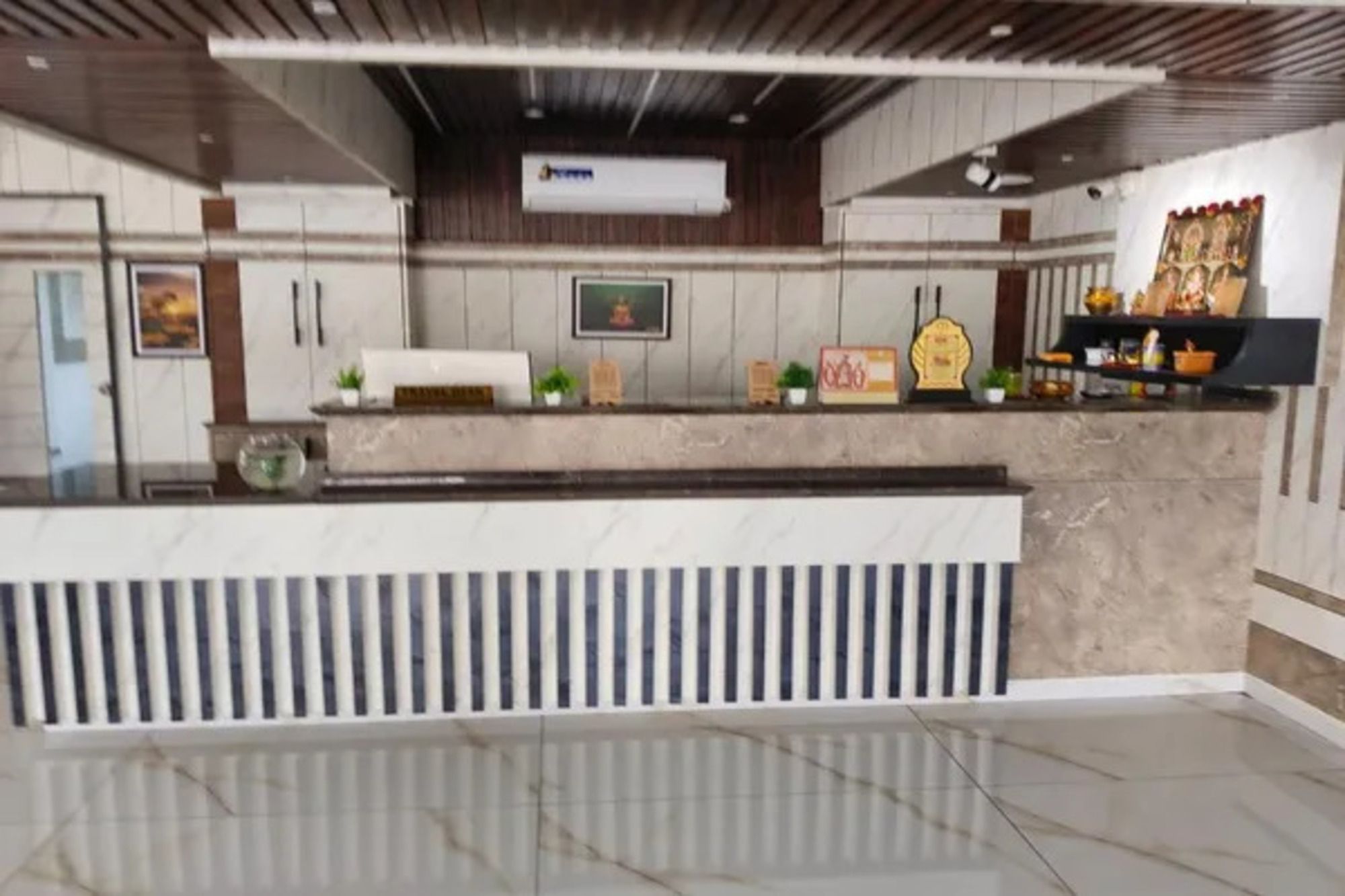 Un'area reception con un bancone in marmo, una ventola a soffitto e un quadro appeso al muro.