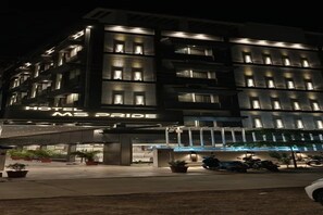 Un hotel de varios pisos con señalización iluminada que dice 'HOTEL MS PRIDE'.