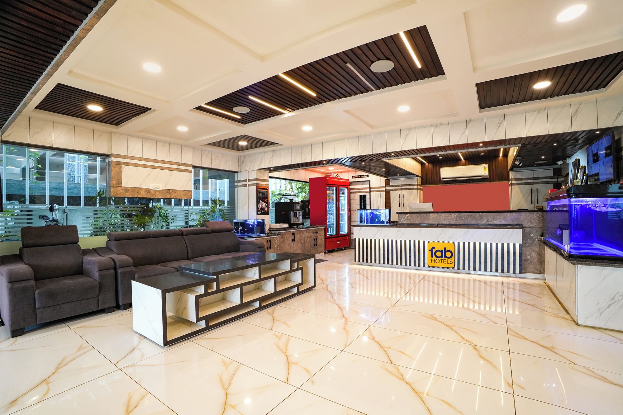 A hotel lobby with a sofa, a coffee machine, a minibar, and a reception desk.