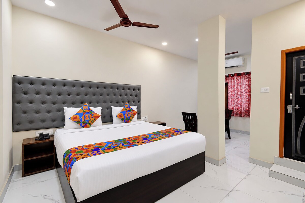 Una habitación de hotel con una cama grande, un ventilador de techo, una mesita de noche y una silla.