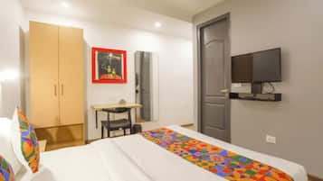 Una habitación de hotel con cama, escritorio, silla, armario, televisión y puerta.