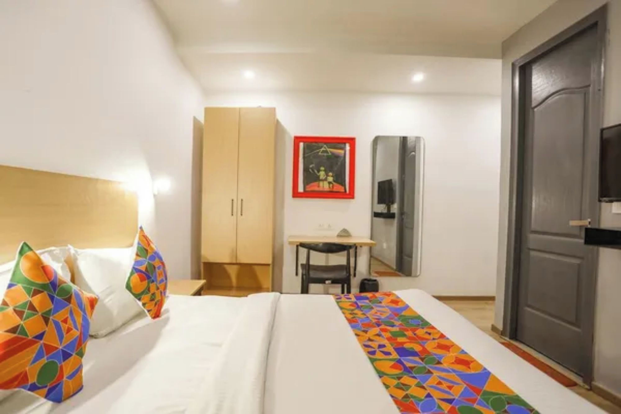 Ein Hotelzimmer mit Bett, Schreibtisch, Kleiderschrank und einer Tür.