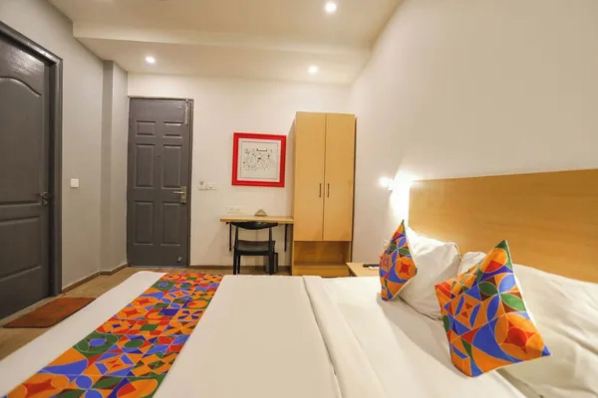 Una habitación de hotel con una cama, un escritorio, una silla y un armario.