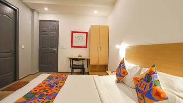 Una habitación de hotel con una cama, un escritorio, una silla y un armario.