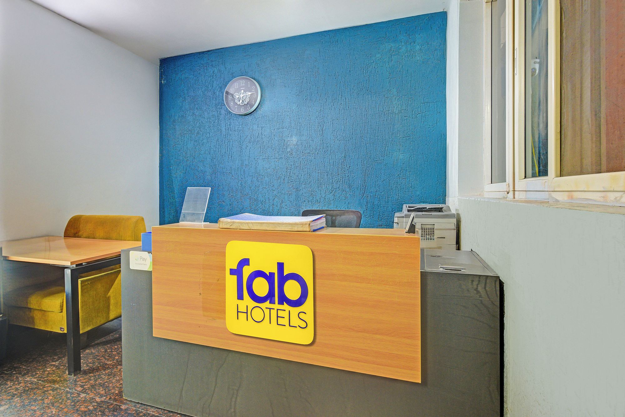 A reception desk with a blue wall and a clock above it.