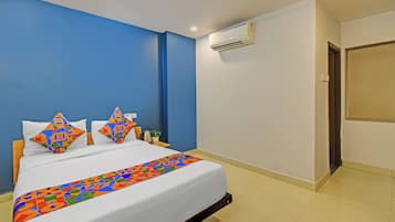 A hotel room with a bed, a nightstand, an air conditioning unit, and a door.