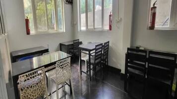 Uma sala de aula com quadro negro, mesas, cadeiras e janelas com extintores.