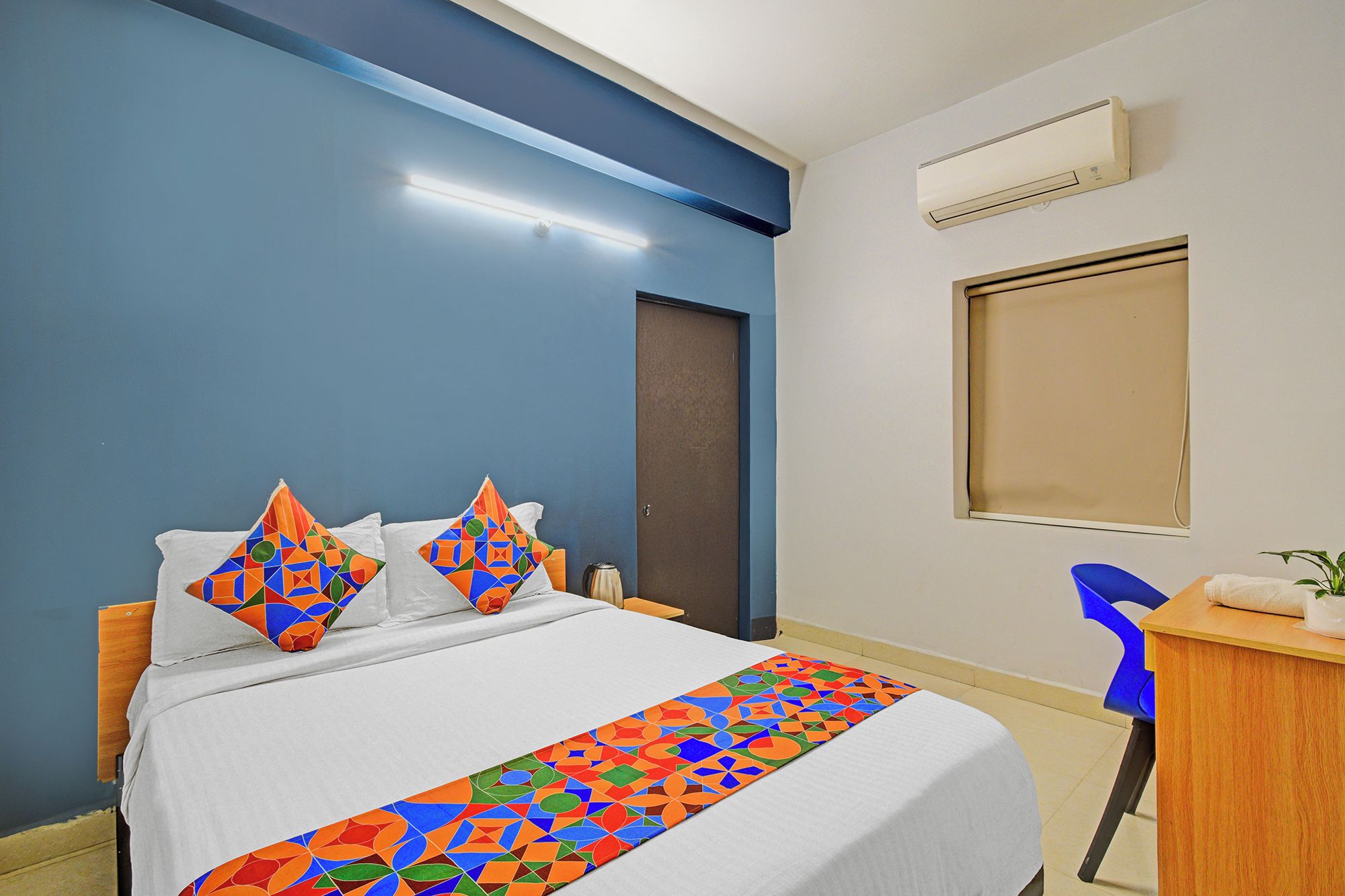 Ein Hotelzimmer mit einem Bett, einem Schreibtisch und einer Klimaanlage.