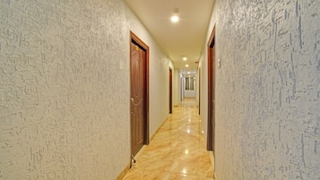 A corridor with patterned walls and a marble floor, leading to a door at the end.