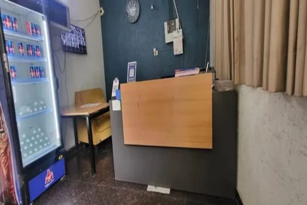 Una taquilla amb un ordinador, un rellotge penjat a la paret i una màquina expenedora.