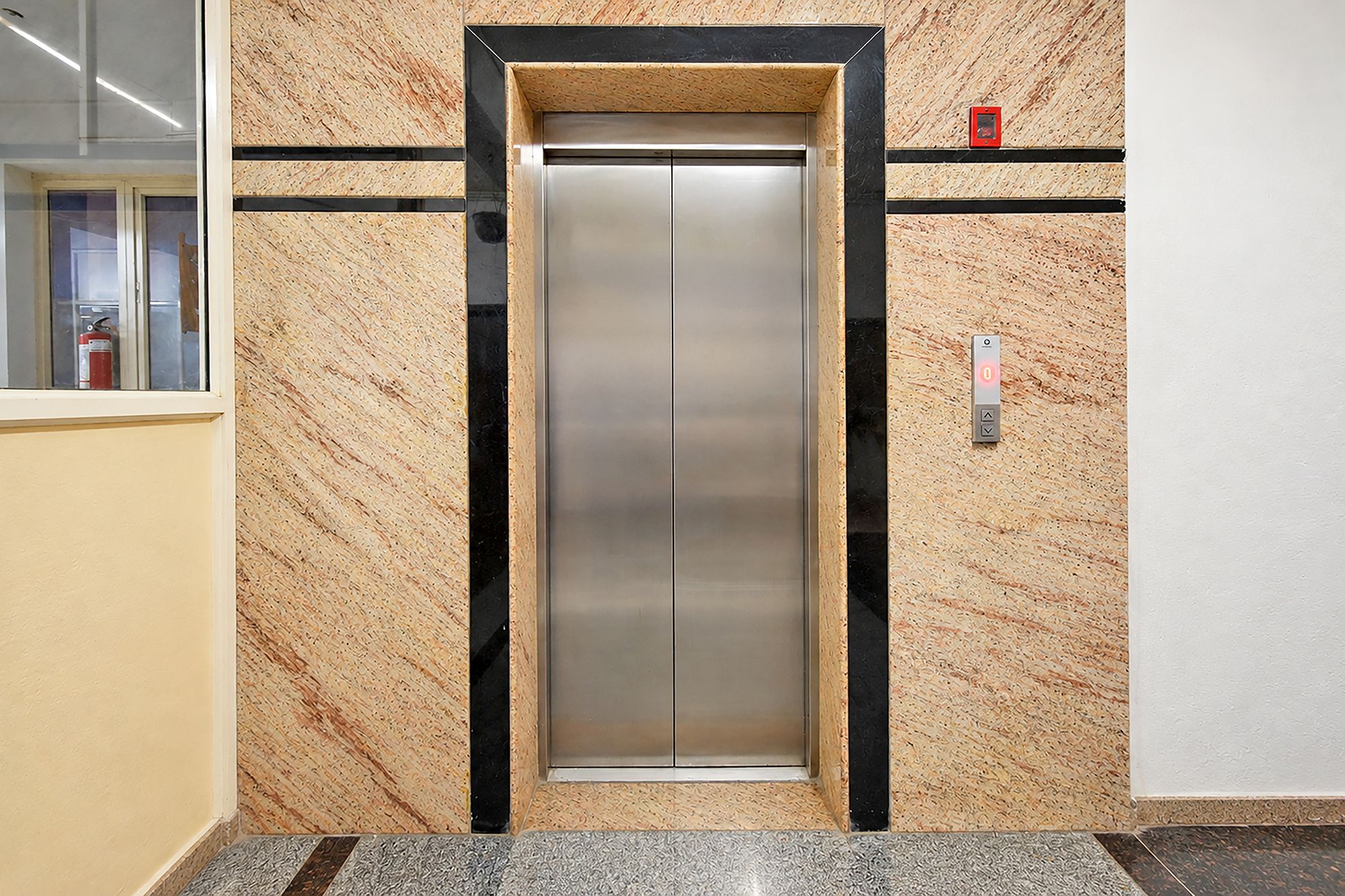 Un ascenseur à l’intérieur métallique, encadré de murs à l’aspect bois et agrémenté de détails noirs.