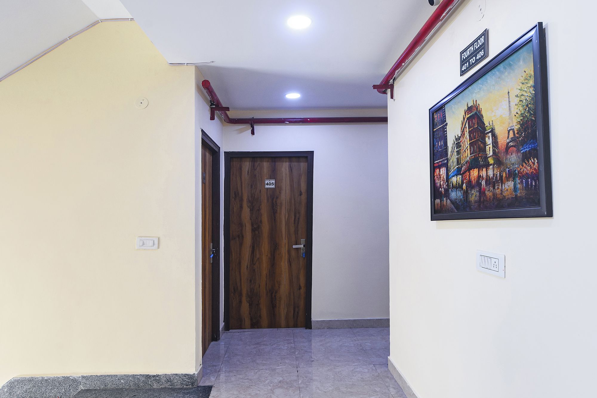 A hallway with a wooden door marked '405', a painting of a cityscape on the wall, and a 'Fourth Floor' sign.