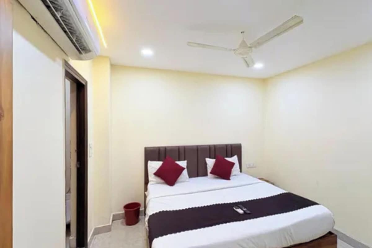A bedroom with a bed, a ceiling fan, and a red bucket.