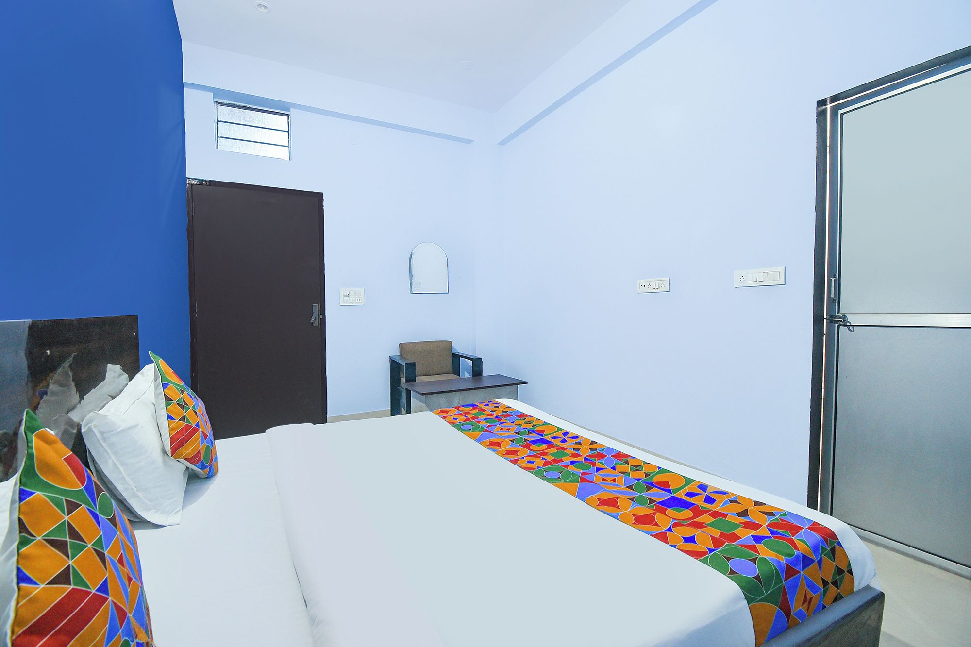 Habitación de hotel con cama, escritorio, silla, armario y ventana.