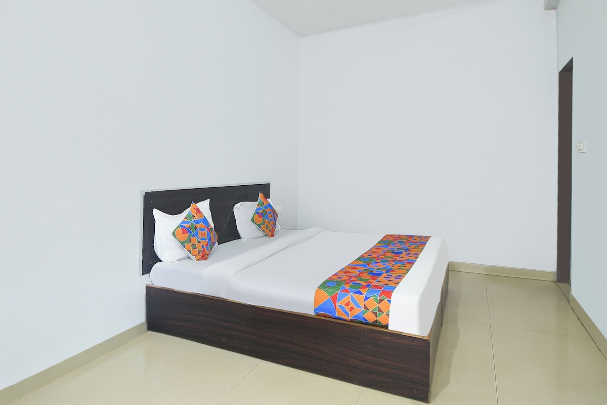 A single bed with a wooden frame, white bedding, and colorful geometric-patterned pillows and bedspread.